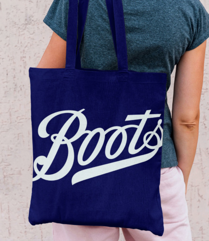 Boots - Purple Boots branded canvas bag slung over someones bag