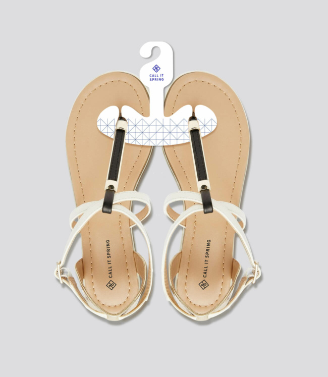Call it spring - A new pair of white/tan sandals on a hanger on a grey background