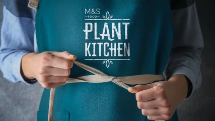 M&S Plant Kitchen - Employee fastening an apron.