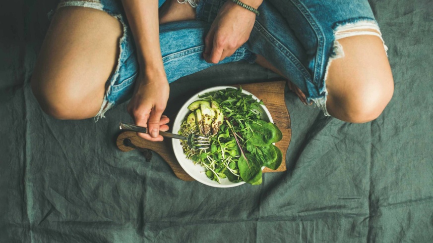 M&S Plant Kitchen - person eating a salad on served on a plate on top of a serving board whilst sitting legs crossed on the floor