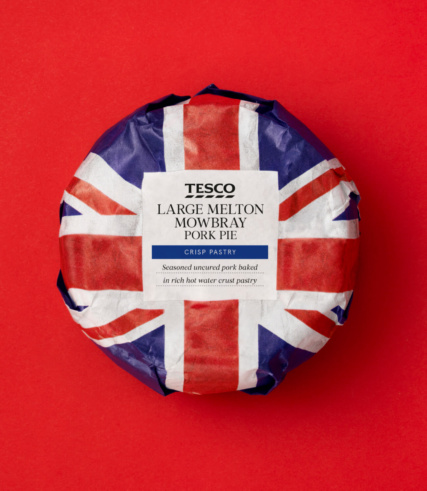 "Tesco Large Melton Mowbray Pork Pie wrapped in Union Jack paper on a red background."