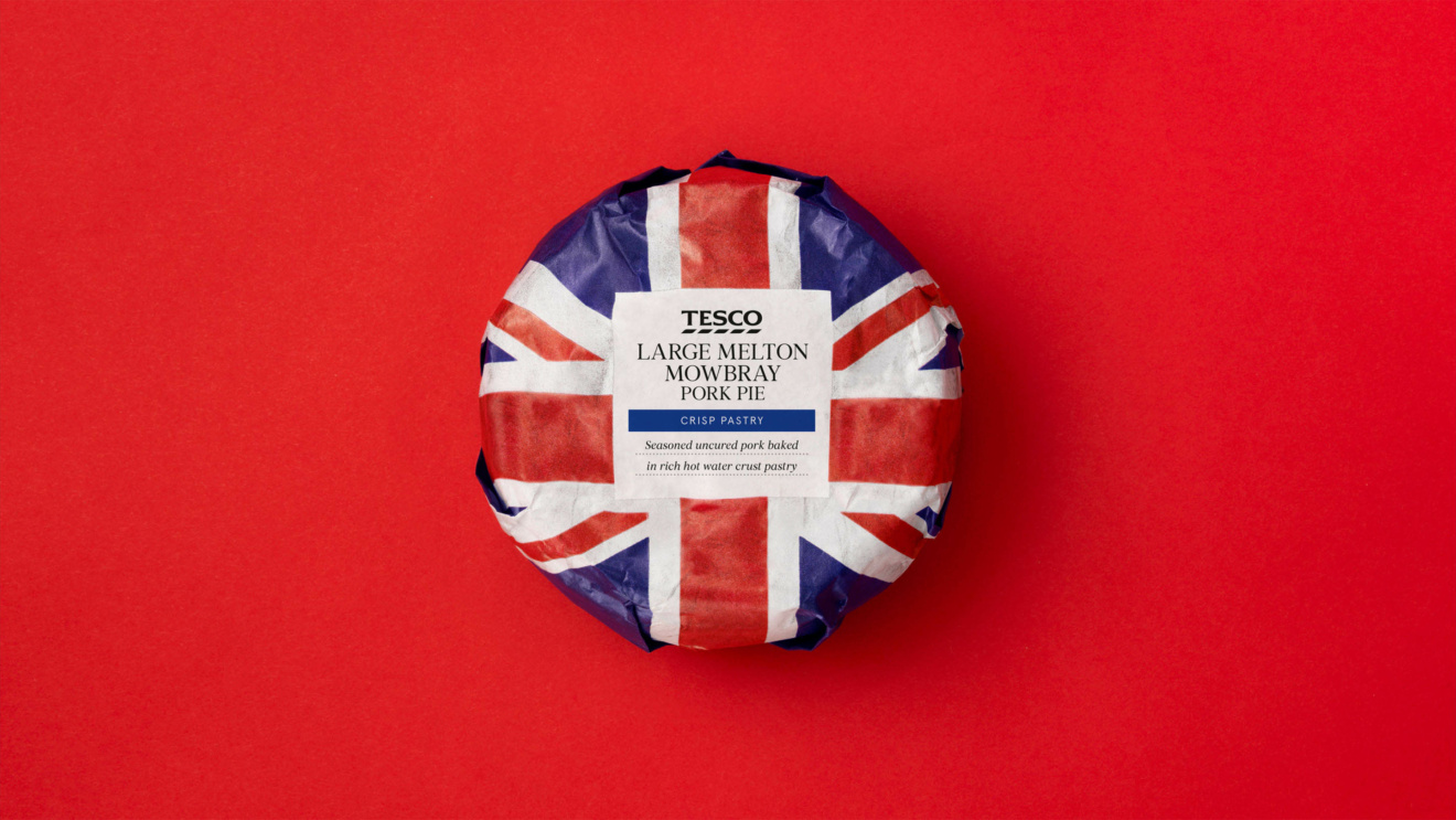 "Tesco Large Melton Mowbray Pork Pie wrapped in Union Jack paper on a red background."