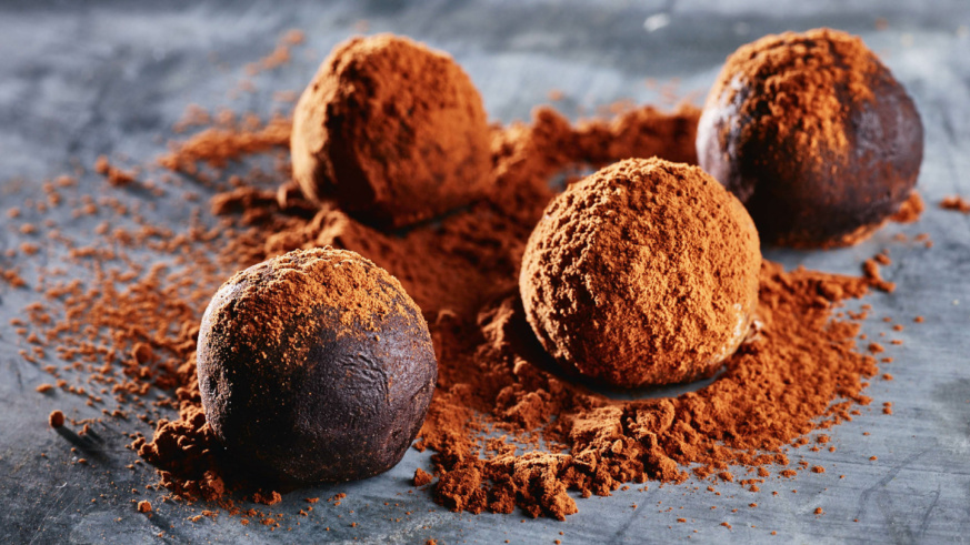 "Rich chocolate truffles dusted with cocoa powder on a textured surface."