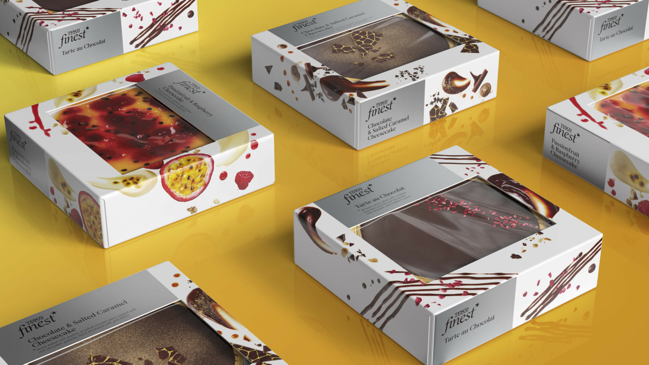 "Various Tesco Finest dessert boxes, including Passionfruit & Raspberry Cheesecake and Tarte au Chocolat, on a yellow surface."