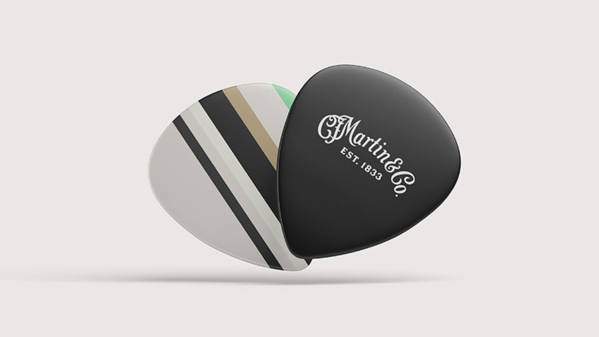 "Two Martin Guitar picks: One black with the Martin logo, one with green, beige, and black stripes.