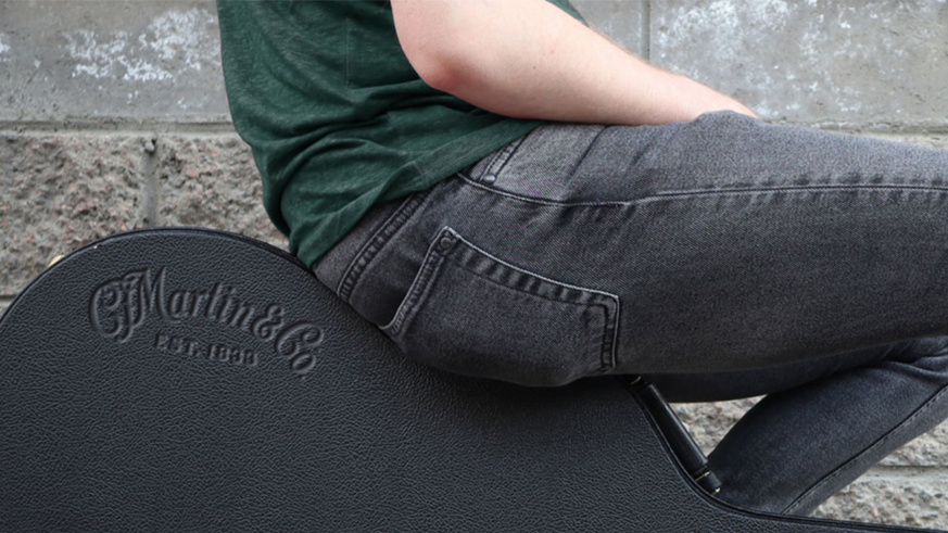 "Person sitting on a Martin Guitar case, showcasing the embossed logo."