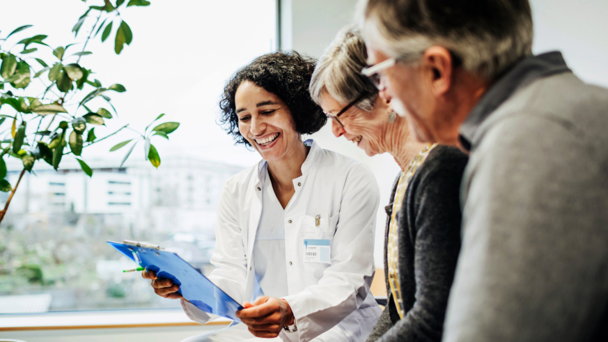 "Doctor smiling and reviewing medical information with senior patients."