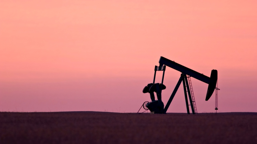 "Example of Cargill's photography princples showing a silhouette of an oil pumpjack against a vibrant pink sunset sky, set in a flat landscape."
